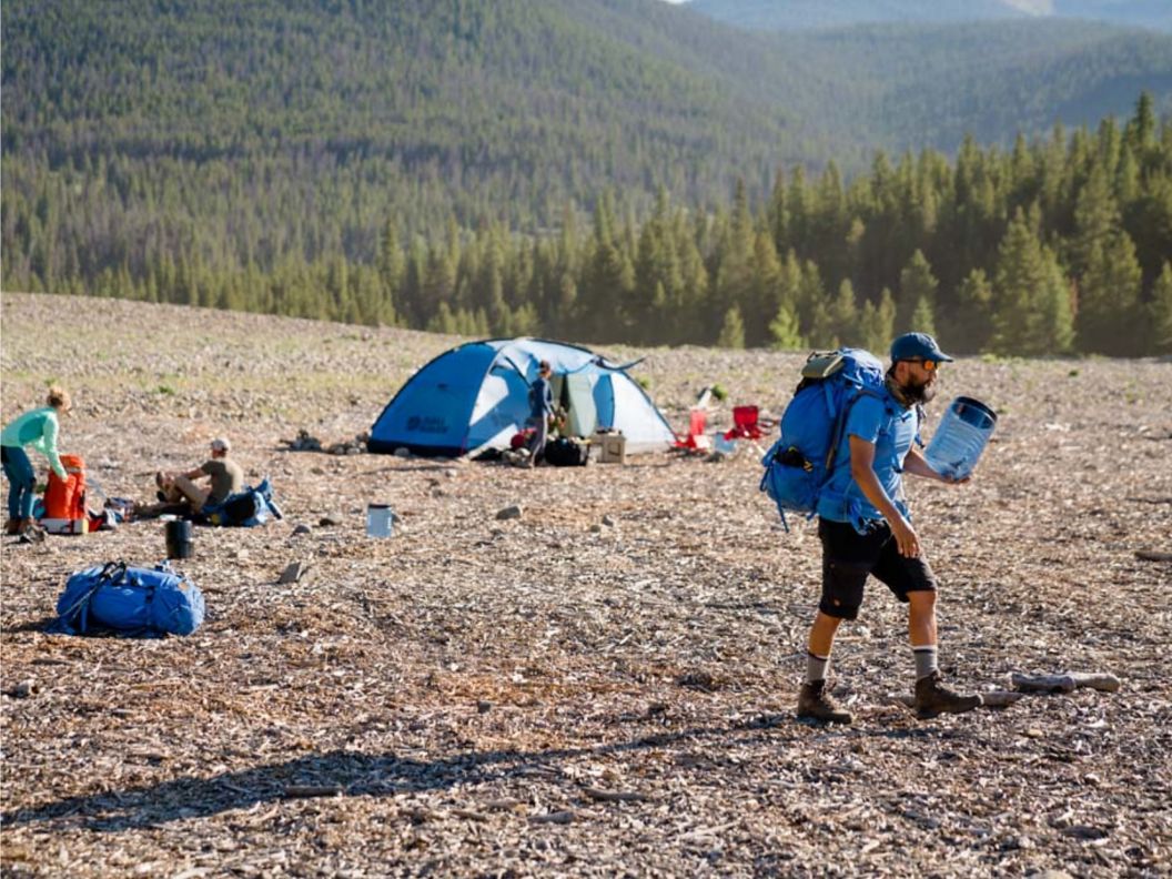 A Man hiking with tents set up on a mountain